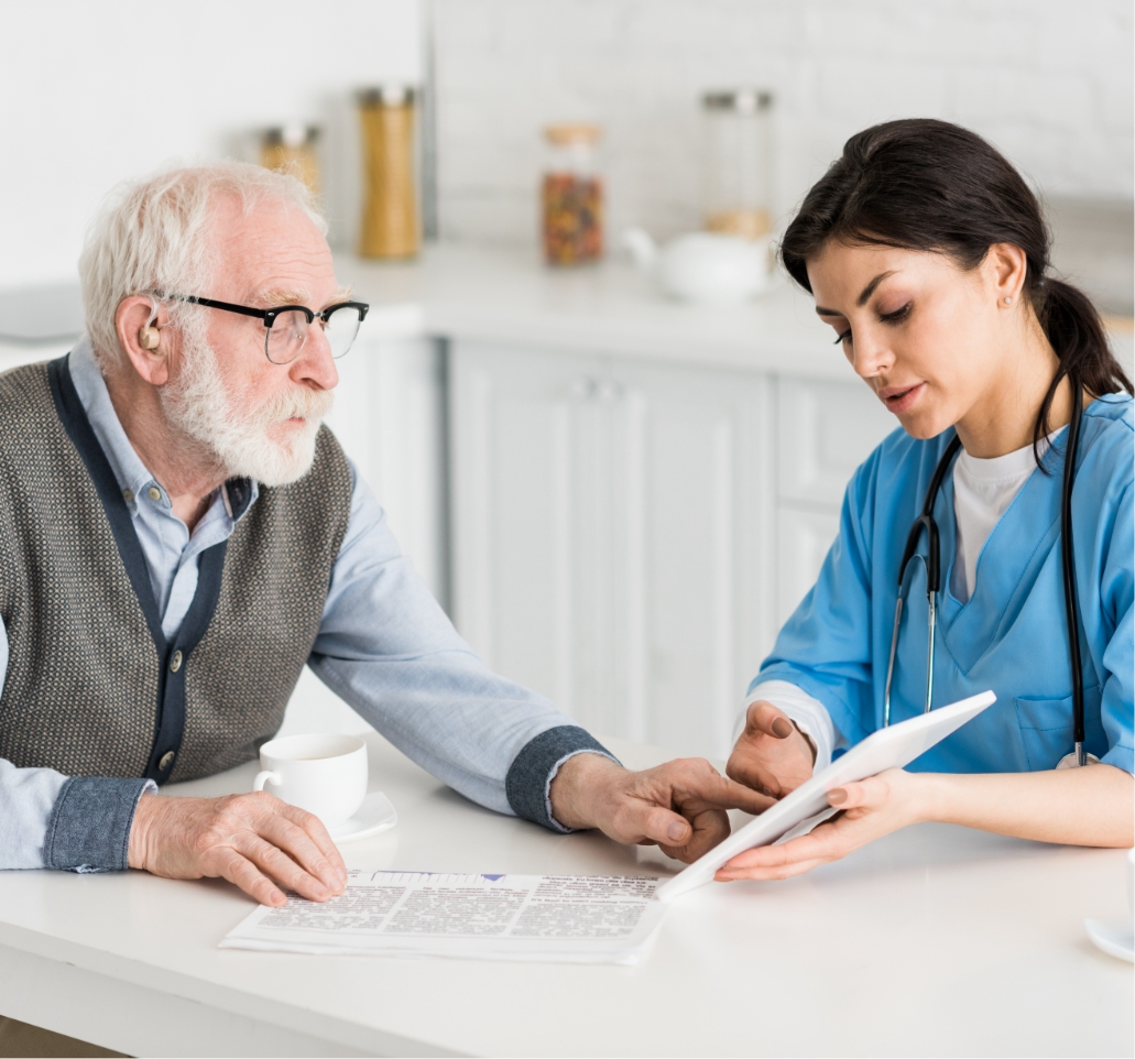 grey haired man talking to nurse on kitchen and us RX97TGG@2x